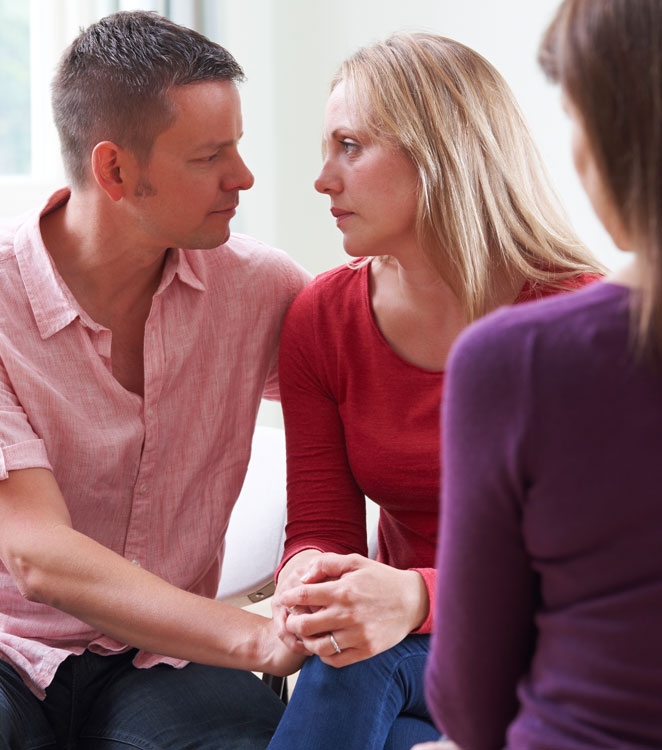 Mature Couple Talking With Counsellor As Man Comforts Woman